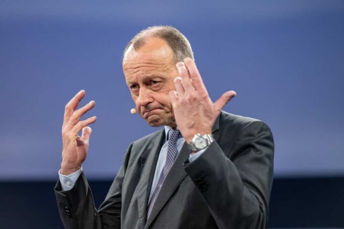 shutterstock_2409460075.jpg A man in a suit gesturing while speaking at a conference