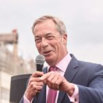 A politician speaking into a microphone at an outdoor event