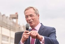 A politician speaking into a microphone at an outdoor event