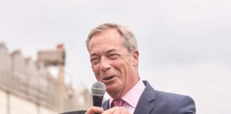 A politician speaking into a microphone at an outdoor event