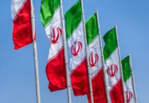 Multiple Iranian flags waving against a clear blue sky