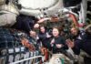 Four astronauts inside a spacecraft, smiling and posing for the camera