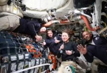 Four astronauts inside a spacecraft, smiling and posing for the camera