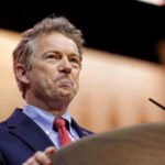 Fauci LIES? Rand Paul Demands DOJ Action A man in a suit speaking at a podium with a serious expression