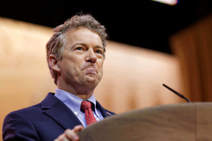 A man in a suit speaking at a podium with a serious expression