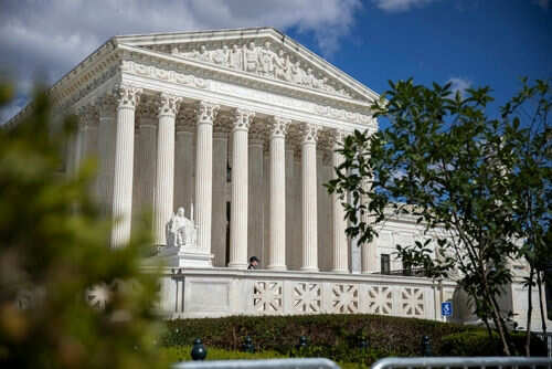 Large neoclassical building with columns behind trees