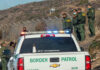 Border Patrol officers speaking with individuals near a fence.