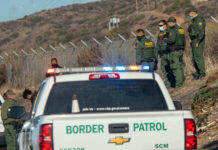 Big Seizures, Bigger Questions For Trump Border Patrol officers speaking with individuals near a fence.