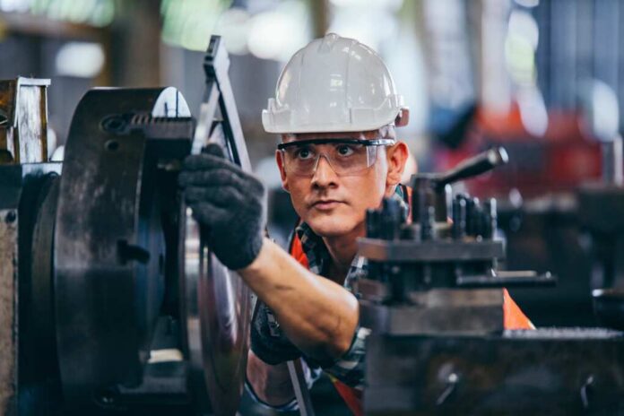 Factory worker adjusting a machine with protective gear