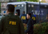 FBI and SWAT team gathered near vehicle.