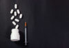 Pills spilled from bottle alongside a syringe