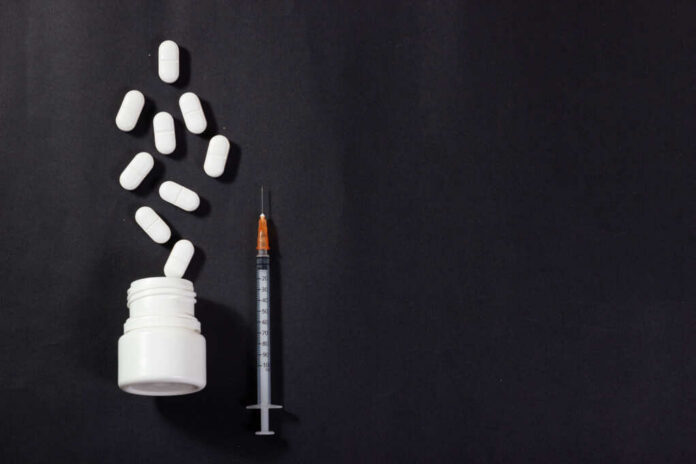 fentanyl2452323549jpg Pills spilled from bottle alongside a syringe