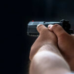 Missing Footage, Dead Dog, Explosive Questions Person holding a black handgun in firing position