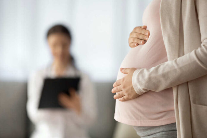 Pregnant person holding their belly during a medical visit