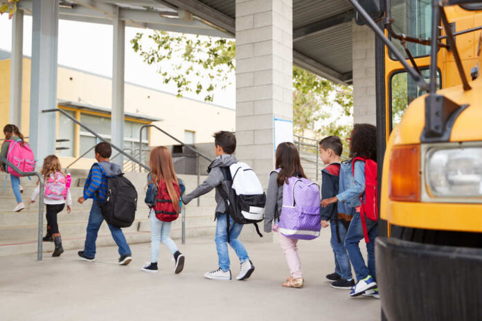 Elementary,School,Kids,Arrive,At,School,From,The,School,Bus Group of children walking towards a school bus