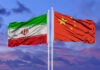 Flags of Iran and China waving against a colorful sky