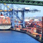 A cargo ship loaded with colorful containers docked at a busy shipping port