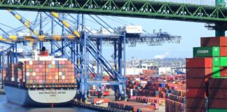 A cargo ship loaded with colorful containers docked at a busy shipping port