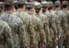 Soldiers in camouflage uniforms standing in formation from behind