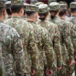 Soldiers in camouflage uniforms standing in formation from behind