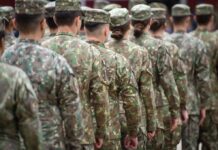 Soldiers in camouflage uniforms standing in formation from behind