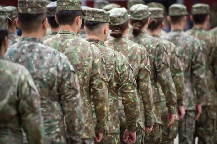 Soldiers in camouflage uniforms standing in formation from behind