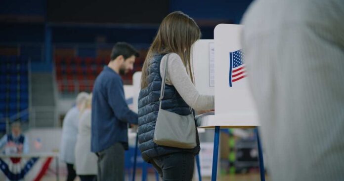 Caucasian,Female,Voter,Comes,With,Bulletin,To,Voting,Booth.,American A person casting their vote at a polling station