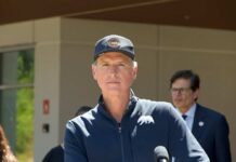 What Is Behind The Newsom Probe? Politician speaking at a press conference outdoors