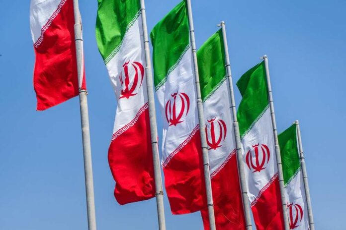 Group,Of,Iran,Flags,Against,Blue,Sunny,Sky,Background Multiple Iranian flags waving against a clear blue sky