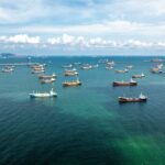 Aerial view of numerous cargo ships anchored in a blue ocean