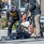Law enforcement officers apprehending a suspect on the ground