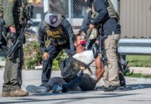 Law enforcement officers apprehending a suspect on the ground
