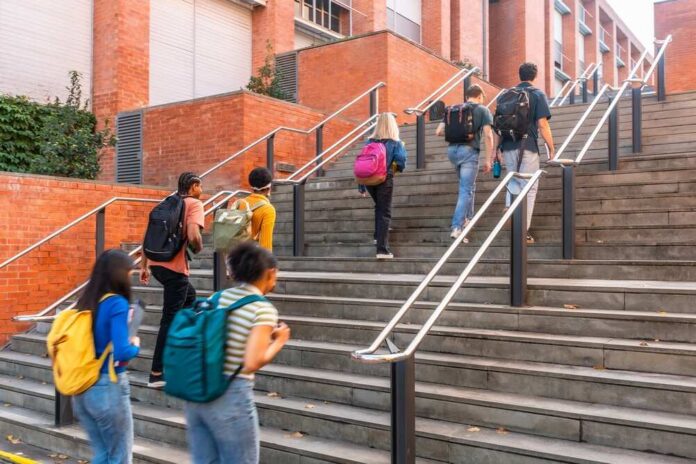 Diverse,Group,Of,University,Students,Climbing,Outdoor,Campus,Stairs,With Group of students ascending outdoor stairs on a campus