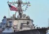 A naval destroyer displaying the American flag and various signal flags