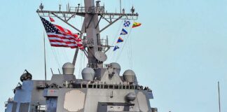 A naval destroyer displaying the American flag and various signal flags