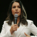 Woman in white suit speaking into a microphone