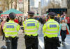 A Street Clash Raises Tough Questions Three police officers in high-visibility jackets stand facing a busy street