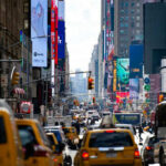 Charlie Kirk Returns To Times Square Busy city street with taxis and billboards daytime
