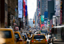 Busy city street with taxis and billboards daytime