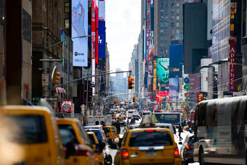 Busy city street with taxis and billboards daytime