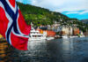 Norwegian flag over harbor with colorful waterfront buildings and boats