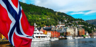 Norwegian flag over harbor with colorful waterfront buildings and boats