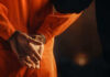 Person in orange jumpsuit with hands cuffed behind back