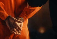 Justice Catches Up To A Deadly Betrayal Person in orange jumpsuit with hands cuffed behind back