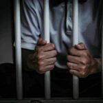 person gripping prison bars