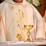Priest celebrating Mass with chalice and open hands