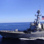 A naval destroyer sailing in the ocean with an American flag