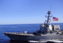 A naval destroyer sailing in the ocean with an American flag