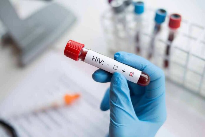shutterstock_1224734254 Gloved hand holding a blood sample tube labeled for HIV test