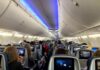 Airplane cabin with passengers seated and seatback screens